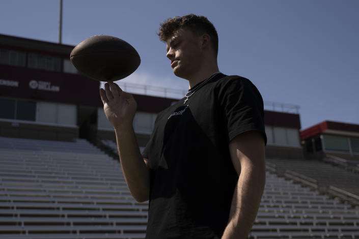 Adam Botkin, a football TikTok influencer, looks on while recording a video for a post at Washington-Grizzly Stadium in Missoula, Mont., on Monday, May 1, 2023. Botkin, a former walk-on place kicker and punter for the Montana Grizzlies, gained notoriety on the social media platform after videos of him performing kicking tricks went viral. (AP Photo/Tommy Martino)