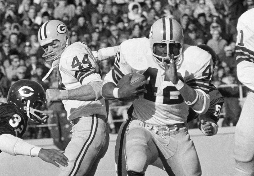 FILE - Green Bay Packers running back John Brockington (42) carries for a first down, past teammate Donny Anderson (44) and Chicago Bears cornerback Charlie Ford (32) during the third quarter of an NFL football game Nov. 7, 1971, in Chicago. Brockington, a former All-Pro fullback who ranks fourth on the Packers’ career rushing list, has died. He was 74. The Packers announced Brockington died Friday, March 31, 2023, in San Diego. (AP Photo/Fred Jewell, File)