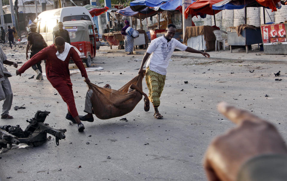 Somalis carry away an injured civilian at the scene of a bomb blast near the Sahafi hotel in the capital Mogadishu, Somalia Friday, Nov. 9, 2018. Four car bombs by Islamic extremists exploded outside the hotel, which is located across the street from the police Criminal Investigations Department, killing at least 20 people according to police. (AP Photo/Farah Abdi Warsameh)