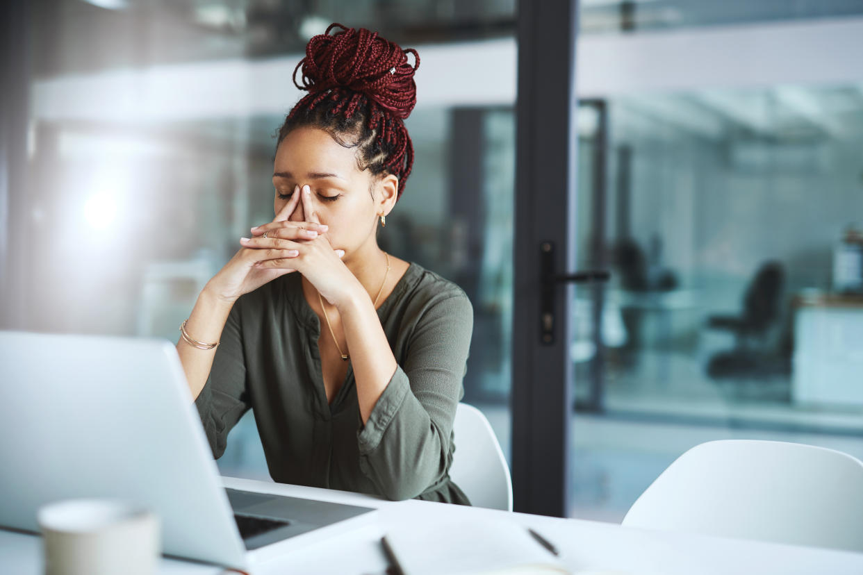 Shot of a young businesswoman looking stressed out while working in an office