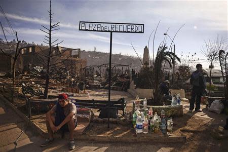 A resident, whose home was damaged by a major fire, sits in Memory Square in the centre of the fire zone in Valparaiso, April 13, 2014. REUTERS/Lucas Ninno