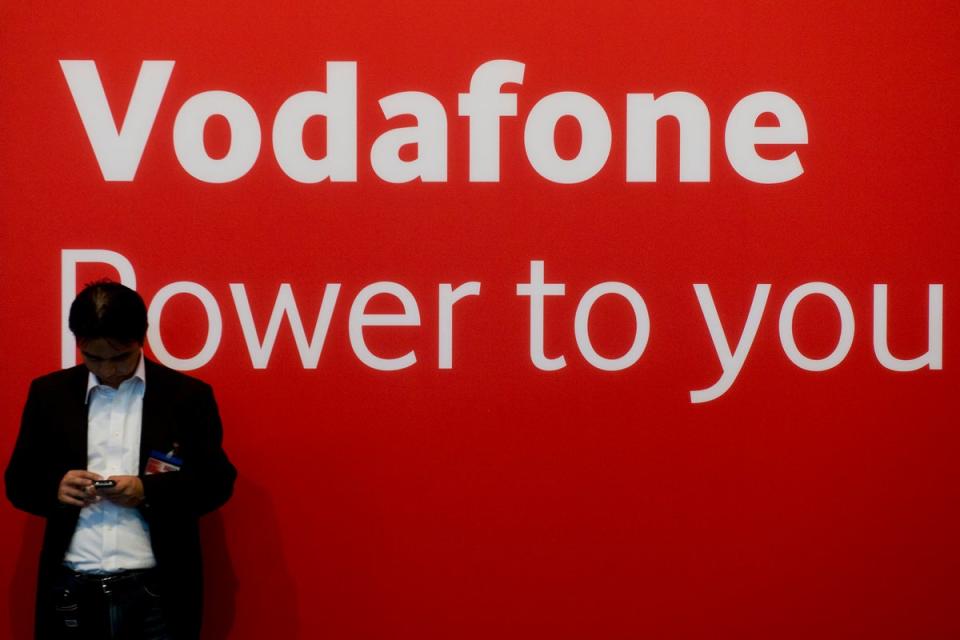 A fair-goer checks his mobile device in front of a Vodafone logo. (AFP/Getty)