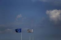 A Greek national flag (R) and a European Union flag flutter atop the Finance ministry building in Athens, Greece June 27, 2015. REUTERS/Alkis Konstantinidis