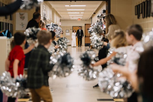 <p>Adam Kennedy Photography</p> Kevin and Catie Zwier walk through the halls of the school after tying the knot