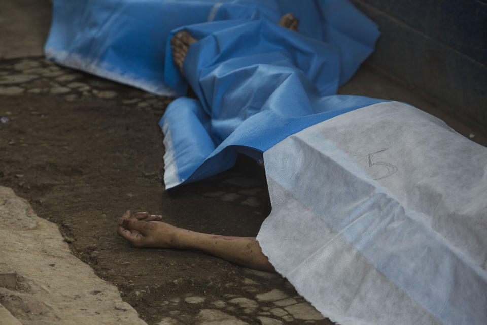 Covered bodies lie inside the entrance area of the Pavon Rehabilitation Model Farm after a shooting inside the jail in Fraijanes, Guatemala, Tuesday, May 7, 2019. Gunfire during a riot in a Guatemala prison Tuesday left at least seven inmates dead and 10 wounded, authorities said. (AP Photo/Oliver De Ros)