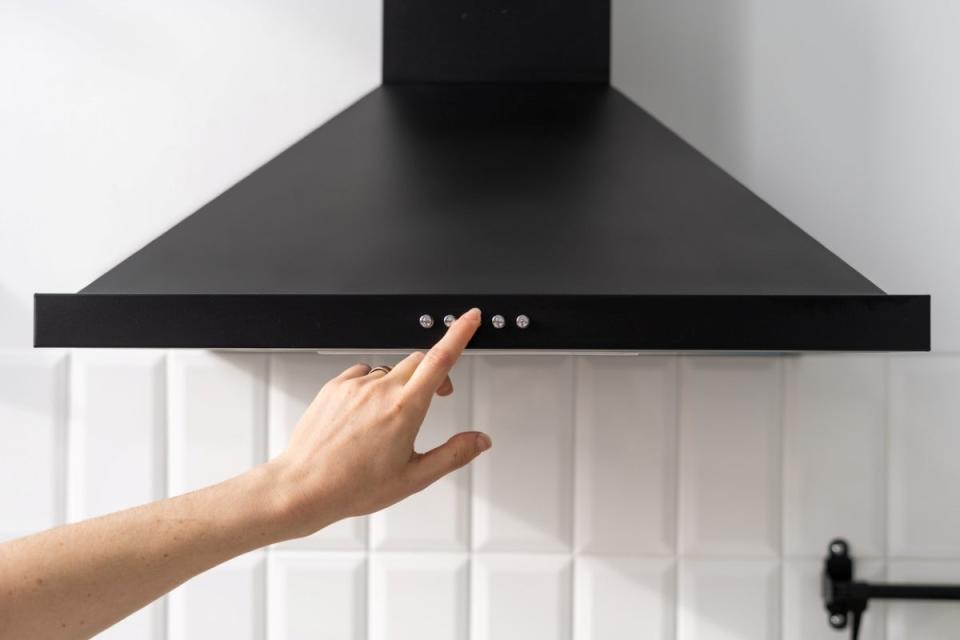 Person turning on a black kitchen range hood