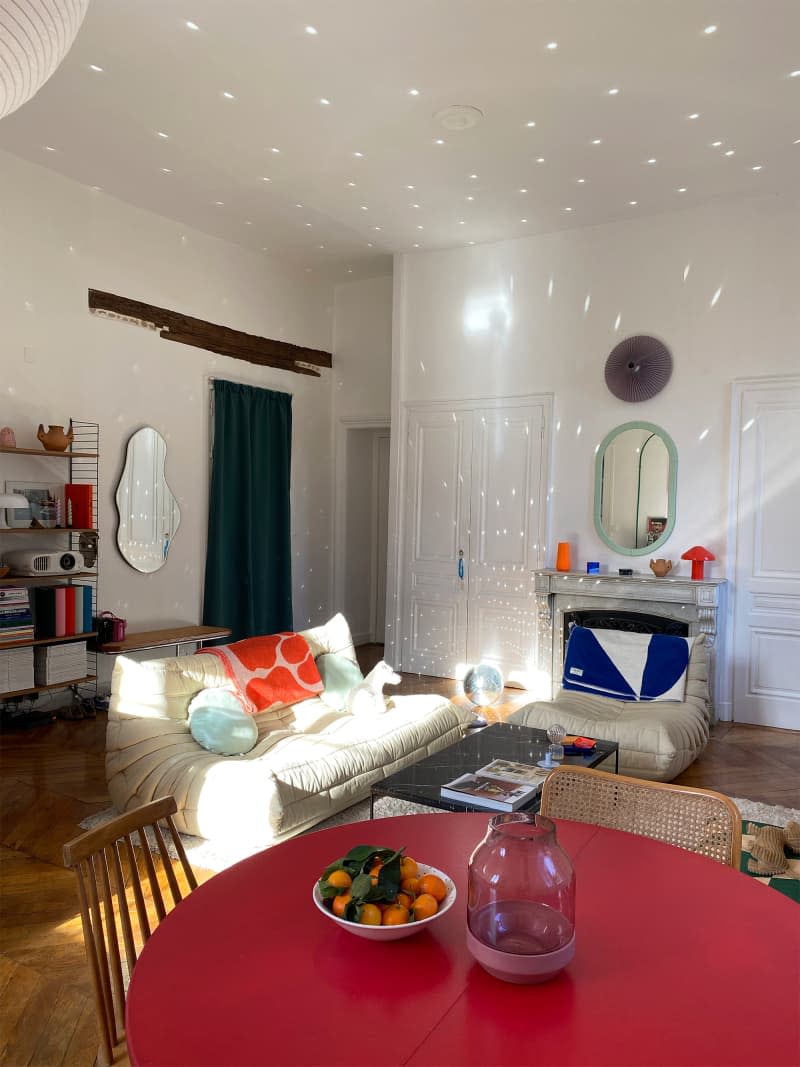 Light reflected around eclectic apartment living room.