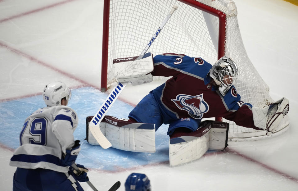 Colorado Avalanche goaltender Alexandar Georgiev, right, makes a glove save of a shot off the stick of Tampa Bay Lightning center Ross Colton in the first period of an NHL hockey game, Tuesday, Feb. 14, 2023, in Denver. (AP Photo/David Zalubowski)