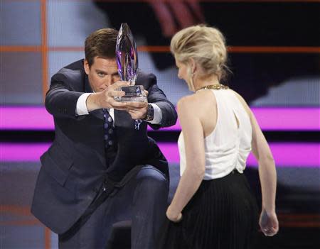 Actor Michael Weatherly kneels as he presents Sarah Michelle Gellar with the award for favorite actress in a new television series for her role in "The Crazy Ones" at the 2014 People's Choice Awards in Los Angeles, California January 8, 2014. REUTERS/Mario Anzuoni