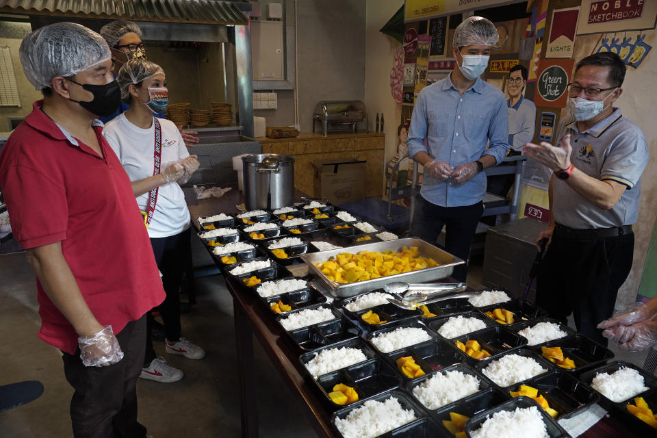 Koh Seng Choon, right, executive director of Dignity Kitchen, talks to volunteers at Dignity Kitchen in Hong Kong on Nov. 17, 2020. Located smack in the middle of Hong Kong's bustling Mong Kok neighborhood, Dignity Kitchen offers an array of mouthwatering Singaporean fare. But what sets Dignity Kitchen apart from other restaurants in the city is that it is a social enterprise, almost entirely staffed by employees with physical or mental disabilities. (AP Photo/Vincent Yu)