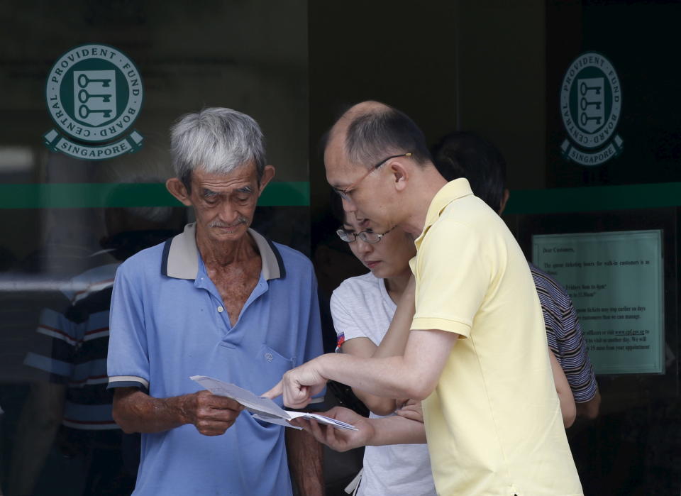 A couple helps read a Central Provident Fund (CPF) statement letter to an elderly man outside a CPF office in Singapore.