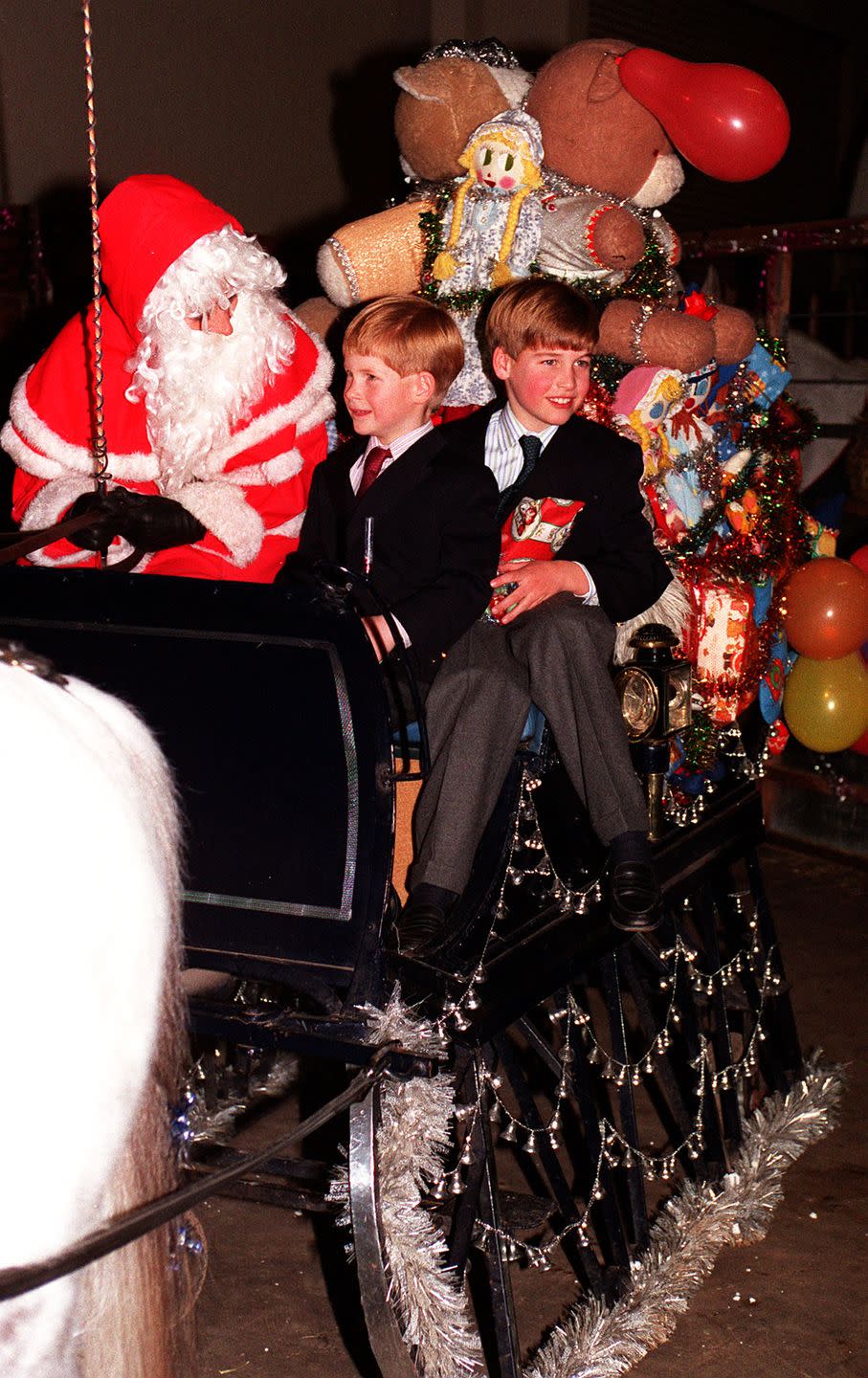 <p>Prince Harry and Prince William sit in a horse-drawn carriage with Santa.</p>