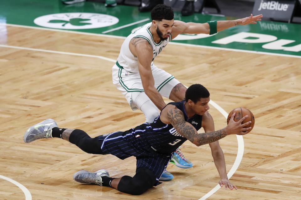 Orlando Magic's Chuma Okeke (3) passes off as he falls in front of Boston Celtics' Jayson Tatum during the first half on an NBA basketball game, Sunday, March 21, 2021, in Boston. (AP Photo/Michael Dwyer)