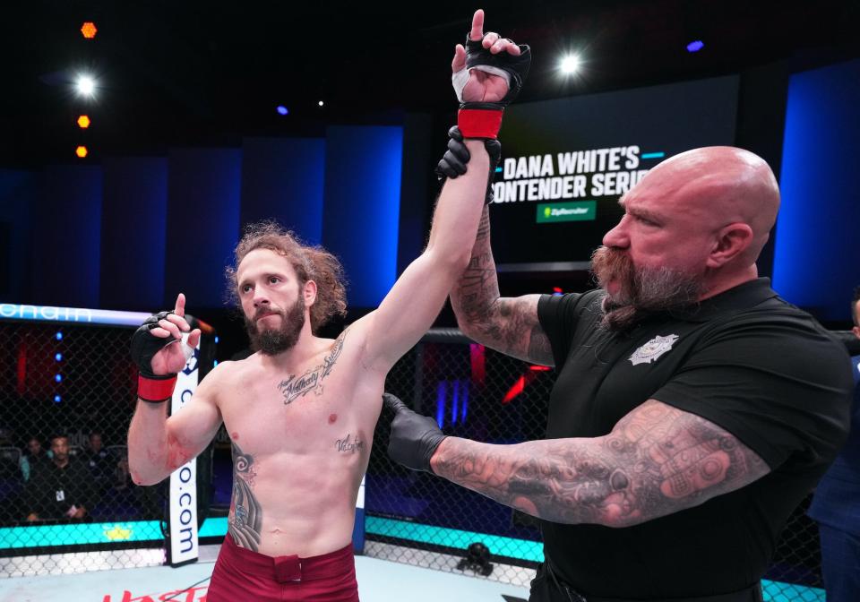 Referee Mike Beltran raises Erik Silva's hand as the winner.