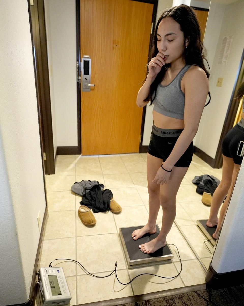 North Central women's wrestling team's Maddie Avila looks down at a scale while she checks for weight before team practice at a team's hotel room in Cedar Rapids, IA., Wednesday, March 6, 2024. North Central women's wrestling team, which happens to be a national powerhouse even though the program is only a few years old and the school is D-III. (AP Photo/Nam Y. Huh)