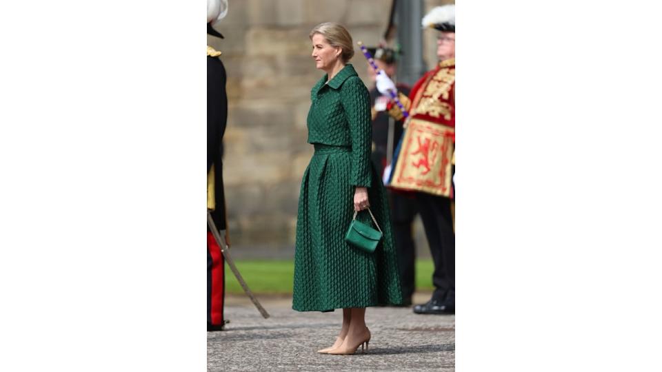 Sophie standing to attention in green skirt and jacket