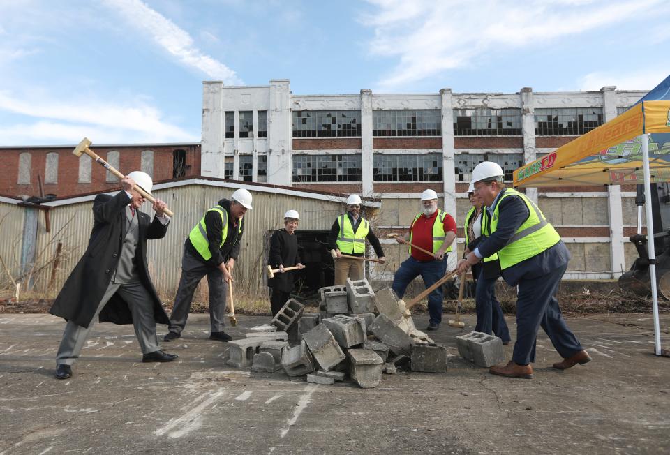 Zanesville Mayor Don Mason, left, Muskingum County Auditor Todd Hixson, Muskingum County Commissioner Cindy Cameron, Land Bank Executive Director Andrew Roberts, land bank board member Rob Sharrer, Commissioner Mollie Crooks, and board member Jody Spence take a ceremonial whack at a pile of cinderblocks during a ceremony to celebrate the start of the demolition of the former Mosaic Tile complex.