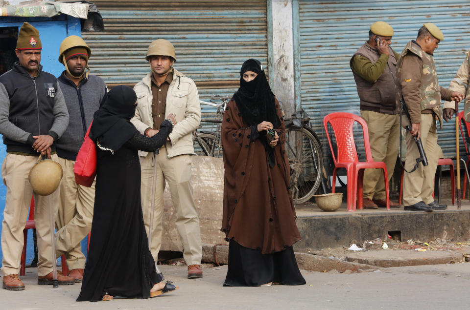 Muslim women cross a street lines with police personnel in Lucknow, in the northern Indian state of Uttar Pradesh, Friday, Dec. 27, 2019. Paramilitary and police forces were deployed and the internet shut down Friday in Muslim-majority districts in Uttar Pradesh, where more than a dozen people have been killed and more than 1,000 people arrested in protests that have erupted nationwide against a new citizenship law that excludes Muslims. (AP Photo/Rajesh Kumar Singh)