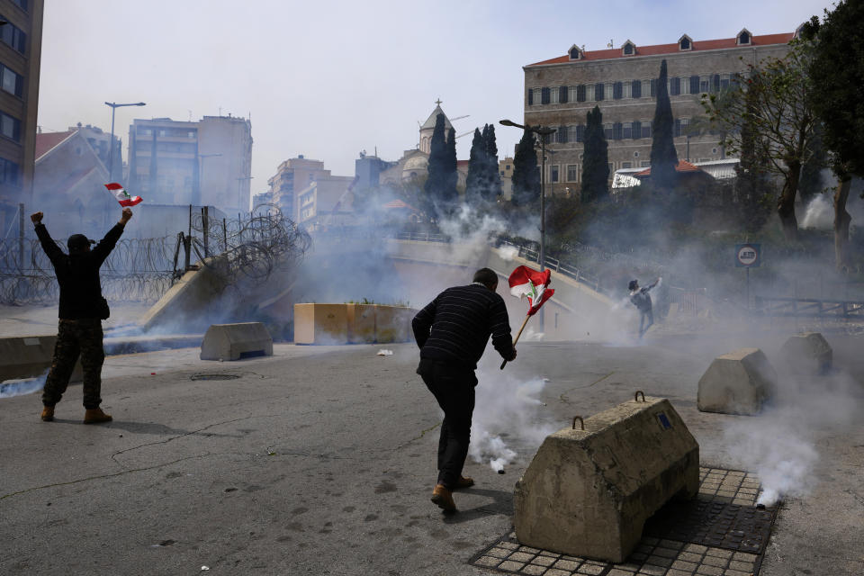 Retired members of the Lebanese security and other protesters return tear gas canisters towards riot police during a protest demanding better pay in Beirut, Lebanon, Wednesday, March 22, 2023. Lebanese security forces fired tear gas to disperse hundreds of protesters who tried to break through the fence leading to the government headquarters in downtown Beirut Wednesday amid widespread anger over the harsh economic conditions in the country. (AP Photo/Hassan Ammar)