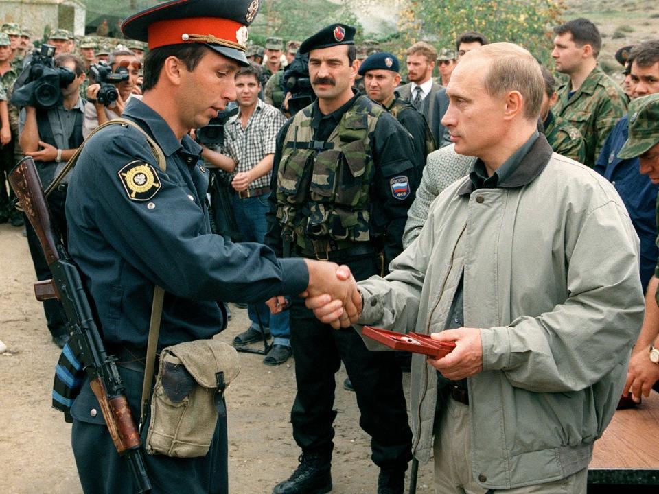 Vladimir Putin shaking a police officer's hand.