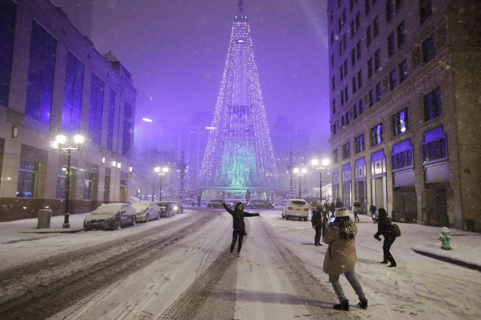 People pose for photos as snow falls in downtown Indianapolis, Sunday, Dec. 15, 2019. (AP Photo/Darron Cummings)