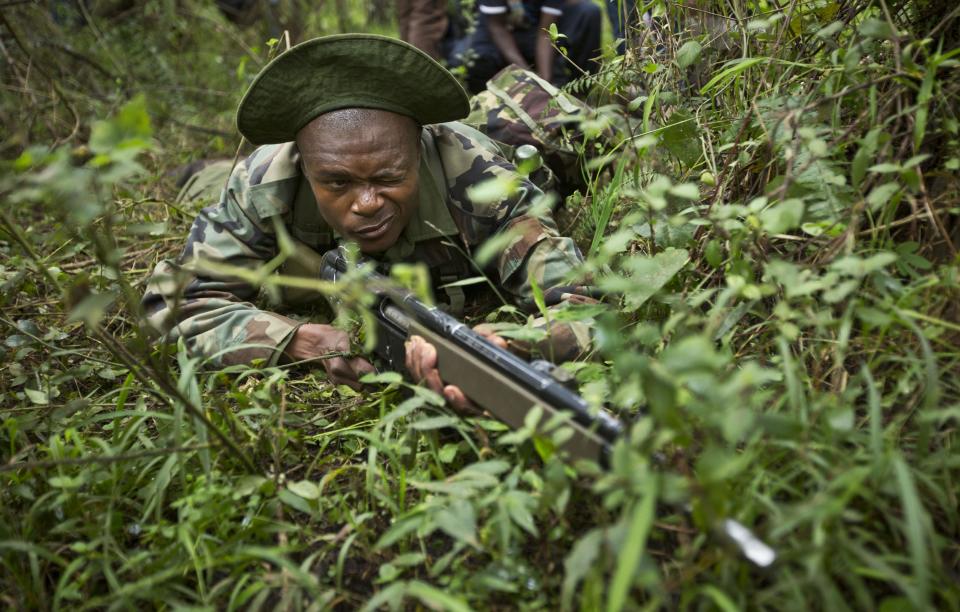 FILE - In this Thursday, Dec. 5, 2013 file photo, rangers of the Kenya Wildlife Service and Kenya Forest Service take cover while engaging in a mock ambush as they stage a demonstration of the skills they have learned over the last few days of joint anti-poaching training with Britain's 3rd Battalion, The Parachute Regiment, in the forest near Nanyuki, Kenya. Kenya's central government will oversee the running of the country's wildlife authority for the next three months in a bid to stop poaching of the country's elephants and rhinos, an official with the Ministry of Environment and Natural resources said Friday, April 11, 2014. (AP Photo/Ben Curtis, File)