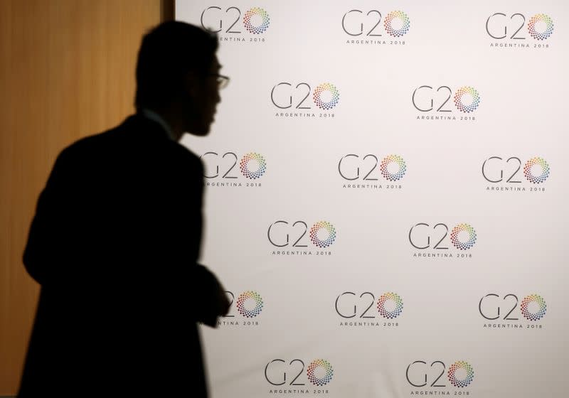 FILE PHOTO: A man stands next to a board with the G20 Meeting of Finance Ministers logo in Buenos Aires