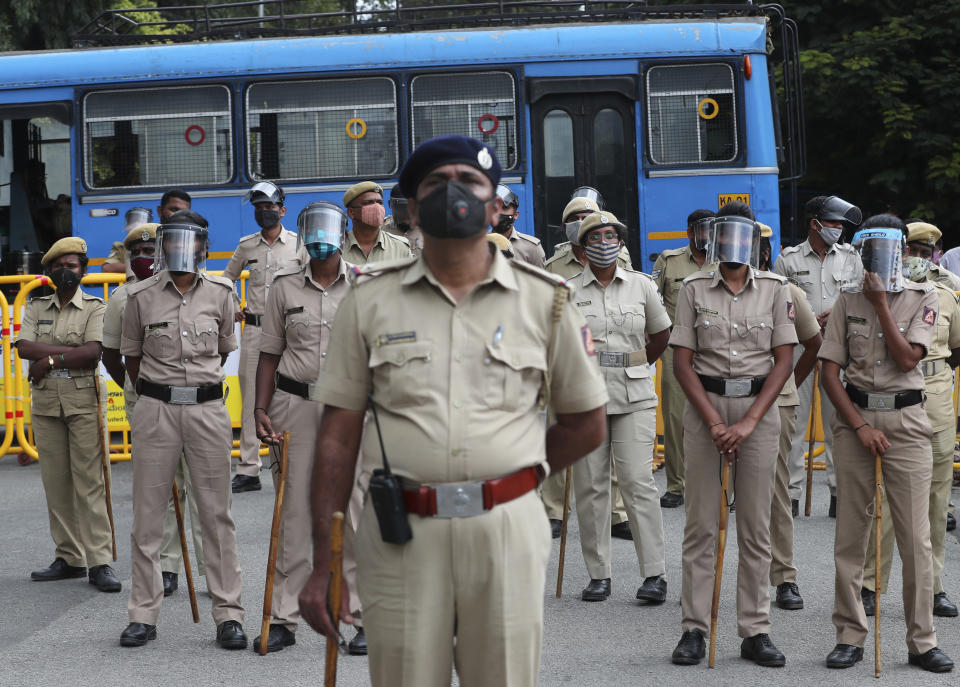 Indian police officials wearing face shields and masks as a precaution against the coronavirus stand guard during a protest against a pair of controversial agriculture bills in Bengaluru, India, Monday, Sept. 28, 2020. India's confirmed coronavirus tally has reached 6 million cases, keeping the country second to the United States in number of reported cases since the pandemic began. (AP Photo/Aijaz Rahi)