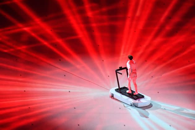 An overview shows a performer walking on a treadmill during the opening ceremony. (Photo: ANTONIN THUILLIER via Getty Images)