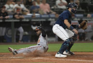 Baltimore Orioles' Cedric Mullins scores a run on a sacrifice fly by Anthony Santander while Seattle Mariners catcher waits for a throw during the ninth inning of a baseball game, Monday, June 27, 2022, in Seattle. (AP Photo/Stephen Brashear)