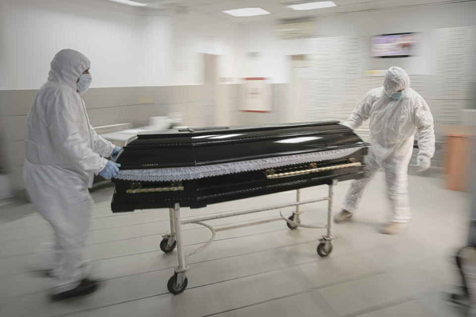 FILE - Funeral house employees drag a coffin on a trolley as they arrive at the University Emergency Hospital morgue to take a COVID-19 victim for burial, in Bucharest, Romania, Monday, Nov. 8, 2021. This was supposed to be the Christmas in Europe where family and friends could once again embrace holiday festivities and one another. Instead, the continent is the global epicenter of the COVID-19 pandemic as cases soar to record levels in many countries. With infections spiking again despite nearly two years of restrictions, the health crisis increasingly is pitting citizen against citizen — the vaccinated against the unvaccinated. (AP Photo/Vadim Ghirda, File)