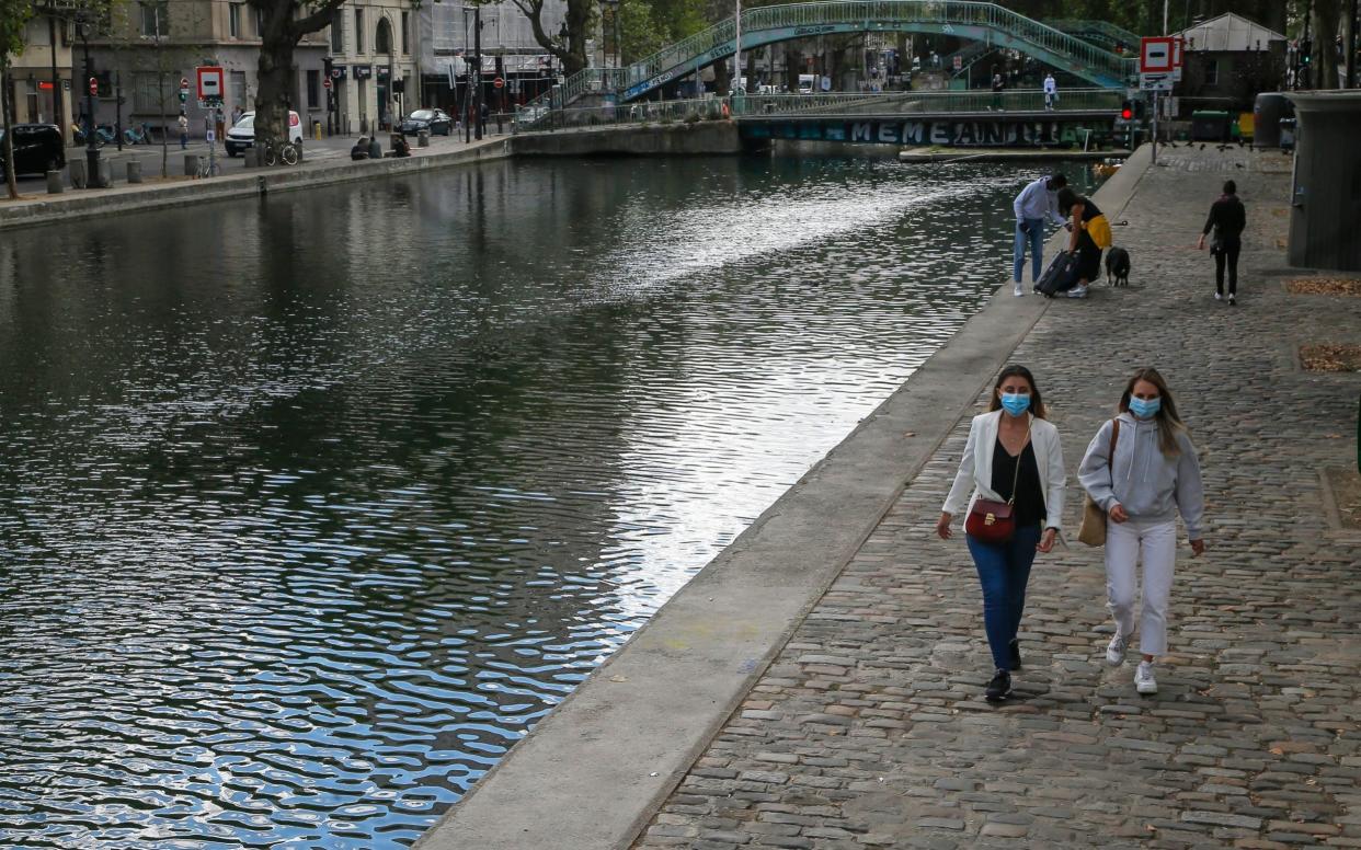 People walk along the canal Saint Martin while wearing protective face masks as a precaution against the coronavirus in Paris - Michel Euler/AP