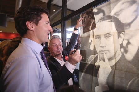 FILE PHOTO: Liberal leader Trudeau looks at a poster of his late fathe during a campaign stop in Sainte-Therese