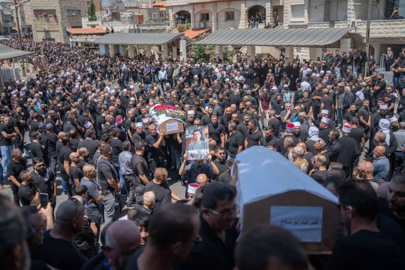 People mourn at the funeral of their relatives in the Druze town of Majd al-Shams in the Israeli-controlled Golan Heights. Several children and young people were killed in a rocket attack on a football field in the village. Ilia Yefimovich/dpa