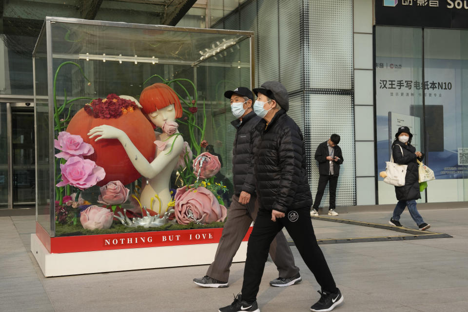 Residents wearing masks past by a sculpture outside a mall in Beijing, Tuesday, Nov. 21, 2023. Chinese leaders have wrapped up a two-day annual meeting to set economic priorities for the coming year, the official Xinhua News Agency reported Tuesday Dec. 12, 2023 without giving details of what was decided. (AP Photo/Ng Han Guan)