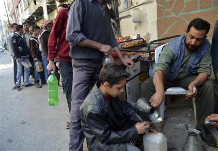 Civilians carry bottles as they queue to buy petrol in eastern al-Ghouta, near Damascus, October 22, 2013. REUTERS/Msallam Abd Albaset