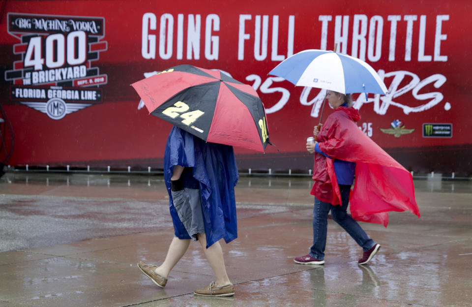 Fans walk under umbrellas as rain delayed track activity for NASCAR's Brickyard 400 at the Indianapolis Motor Speedway in Indianapolis, Saturday, Sept. 8, 2018. (AP Photo/Michael Conroy)