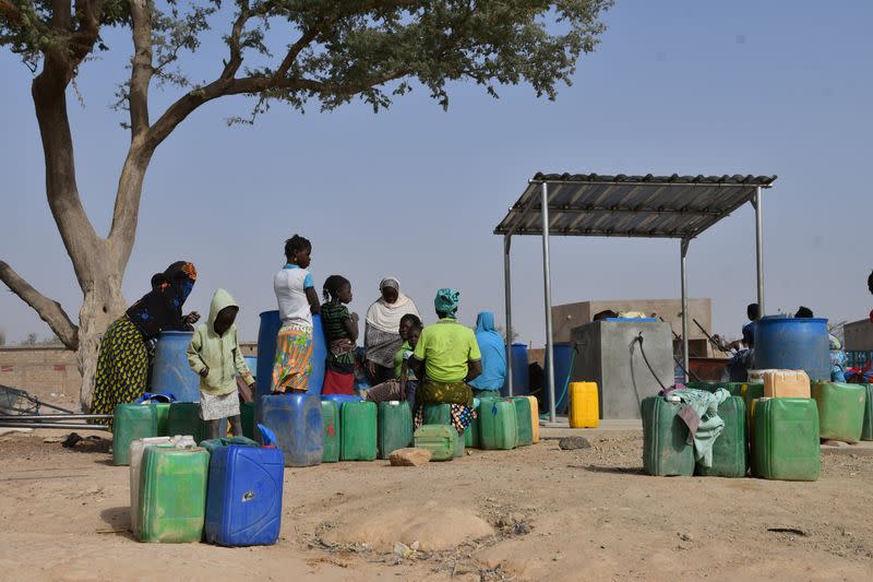 Displaced people, who fled from attacks of armed militants in town of Roffenega, wait to fill their jerrycans at the water point near UNHCR camp in Pissila