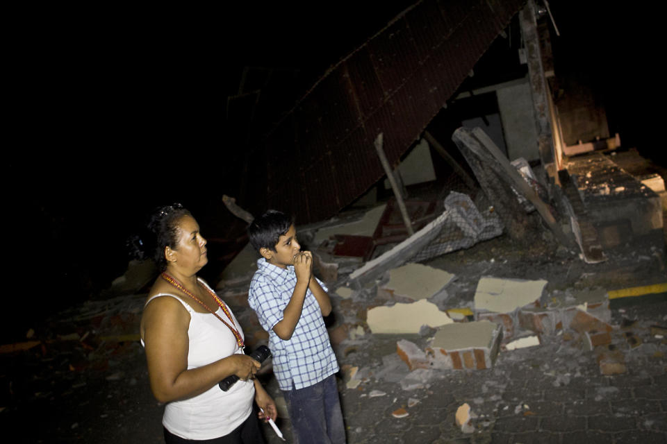 A woman and boy stand near a home that was damaged by an earthquake in Nagarote, Nicaragua, Thursday, April 10, 2014. A 6.1-magnitude earthquake damaged dozens of houses in western Nicaragua on Thursday, and authorities said some people were injured by falling ceilings, beams and walls. (AP Photo/Esteban Felix)