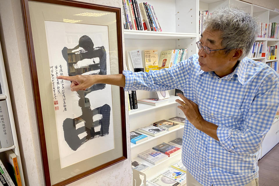 Lam Wing-Kee, a Hong Kong bookstore owner who fled to Taiwan in 2019, gestures at a calligraphy with the words "Freedom" during an interview inside his bookstore in Taipei, Taiwan on June 8, 2022. Coming to Taiwan was a logical step for Lam, a Hong Kong bookstore owner who was held by police in China for five months for selling sensitive books about the Communist Party. An island just 400 miles from Hong Kong, Taiwan is close not just geographically but also linguistically and culturally. (AP Photo/Johnson Lai)