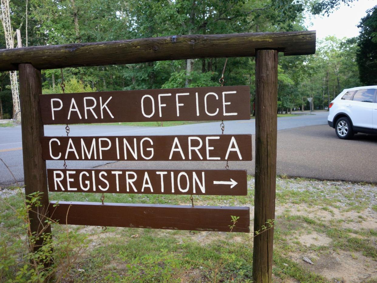 Close up of park office camping area registration road arrow sign with passing car in public state park.