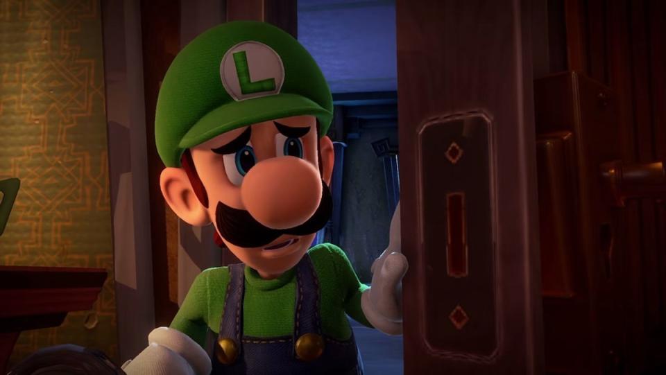 A scared Luigi in his green hat opens a door in Luigi's Mansion