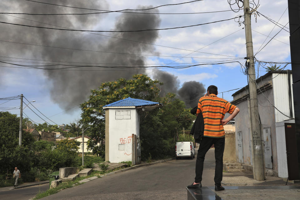 A man talks on a phone as smoke rises in the air after shelling in Odesa, Ukraine, Saturday, July 16, 2022. (AP Photo/Nina Lyashonok)