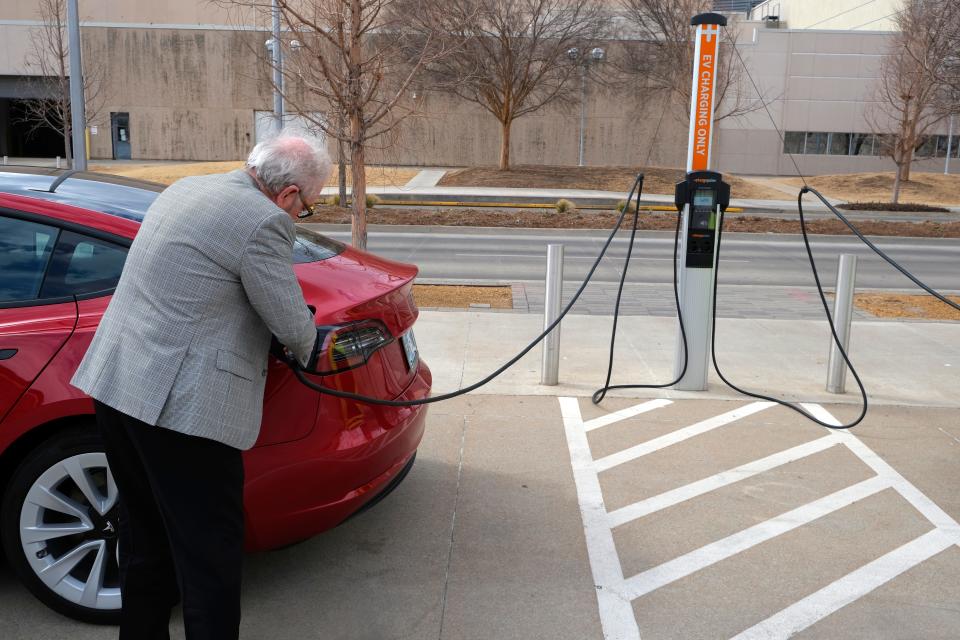 Jim Holman plugs in his Tesla Model 3 on March 4, 2022, at the EV charging station in the Santa Fe Station parking lot on E.K. Gaylord Boulevard.