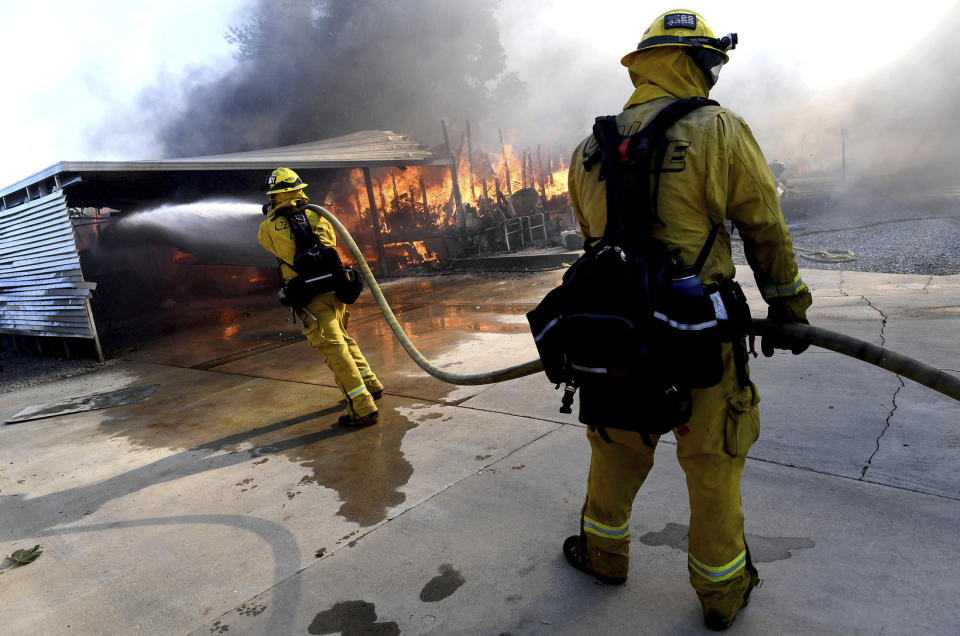 Firefighters try to protect surrounding homes as they battle the Sandalwood Fire in the Villa Calimesa Mobile Home Park in Calimesa, Calif., on Thursday, Oct. 10, 2019. Burning trash dumped along a road sparked a wildfire Thursday that high winds quickly pushed across a field of dry grass and into a Southern California mobile home park, destroying dozens of residences. (Jennifer Cappuccio Maher/The Orange County Register/SCNG via AP)