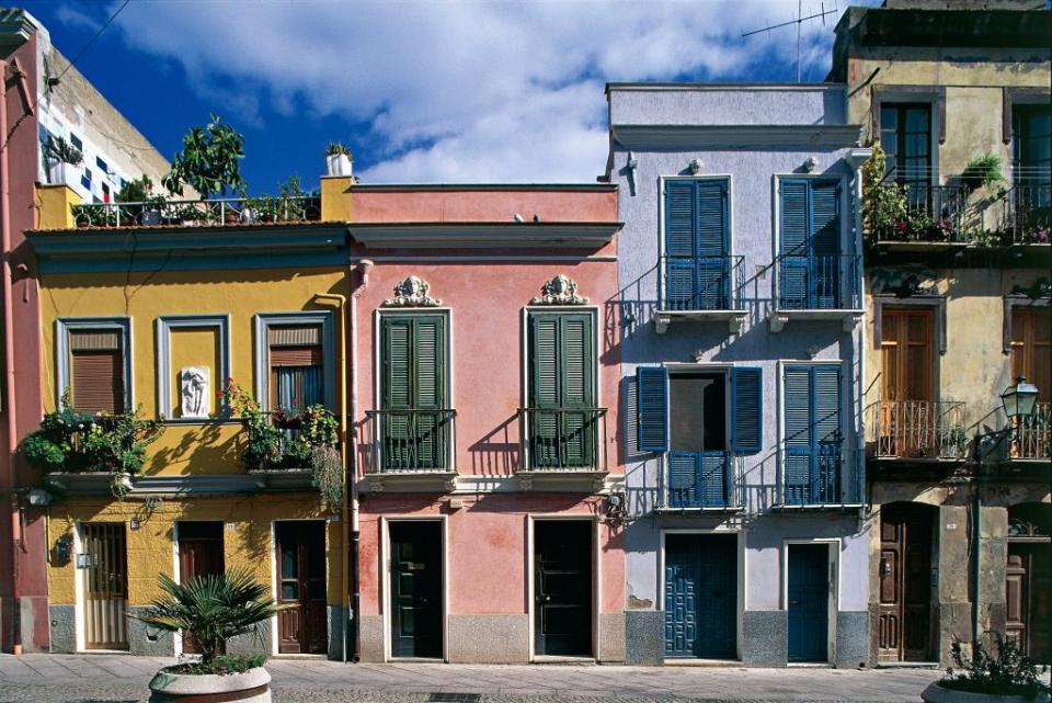 <p>Pale pastel row houses soak up the warm Italian sun in Sardinia.</p>