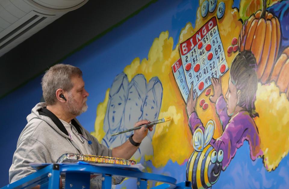 Artist Greg Preslicka works on a mural in the library on April 18 at Martin Elementary in Green Bay.