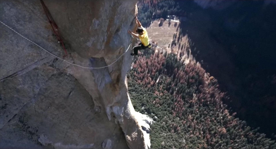 Alex Honnold hangs off the side of a cliff