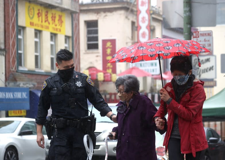 SAN FRANCISCO, CALIFORNIA - MARCH 18: San Francisco police officer William Ma (L) helps an elderly woman cross the street while on a foot patrol in Chinatown on March 18, 2021 in San Francisco, California. The San Francisco police have stepped up patrols in Asian neighborhoods in the wake of a series of shootings at spas in the Atlanta area that left eight people dead, including six Asian women. The San Francisco Bay Area is also seeing an increase in violence against the Asian community. (Photo by Justin Sullivan/Getty Images)