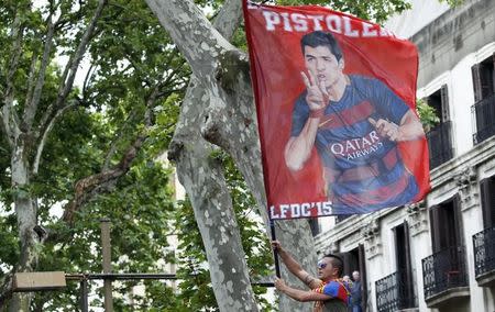 A Barcelona's fan waves a flag with the image of soccer star Luis Suarez as he celebrates over a lamppost after winning the Spanish first division soccer championship in Barcelona, Spain, May 14, 2016. REUTERS/Juan Medina